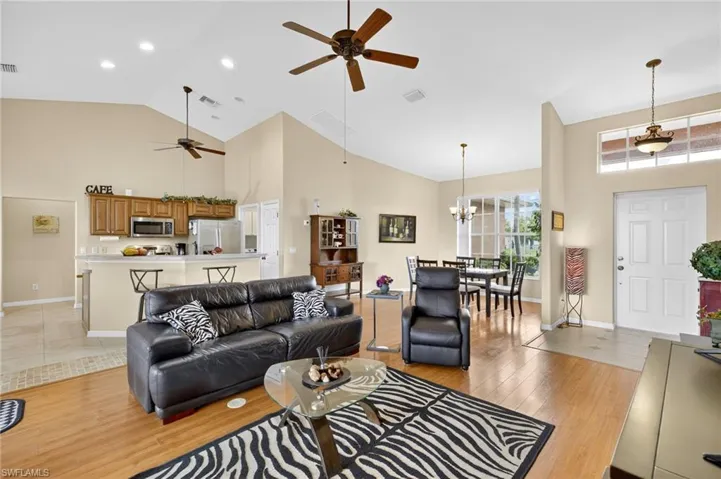 Living area with ceiling fan, high vaulted ceiling, light wood-style flooring, a chandelier, and recessed lighting