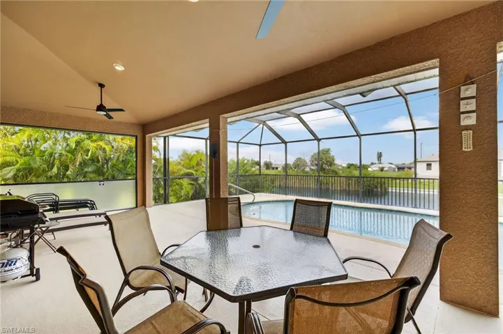 View of patio featuring a ceiling fan, a water view, glass enclosure, and outdoor dining space