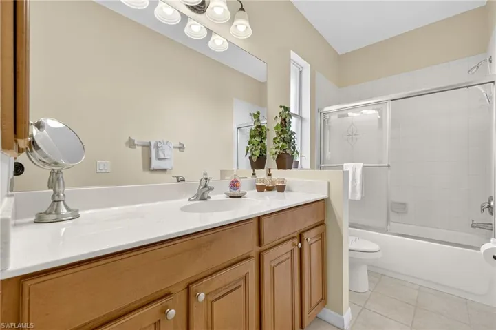 Bathroom featuring vanity, tile patterned flooring, and shower / bath combination with glass door