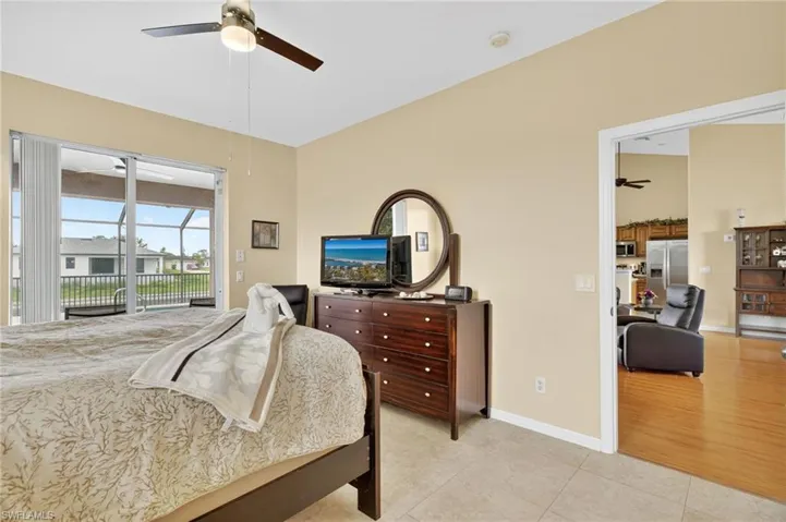 Bedroom with stainless steel fridge, access to exterior, light tile patterned floors, and ceiling fan