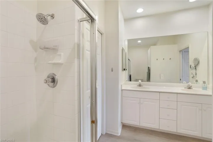 Bathroom with hardwood / wood-style flooring, vanity, and a tile shower