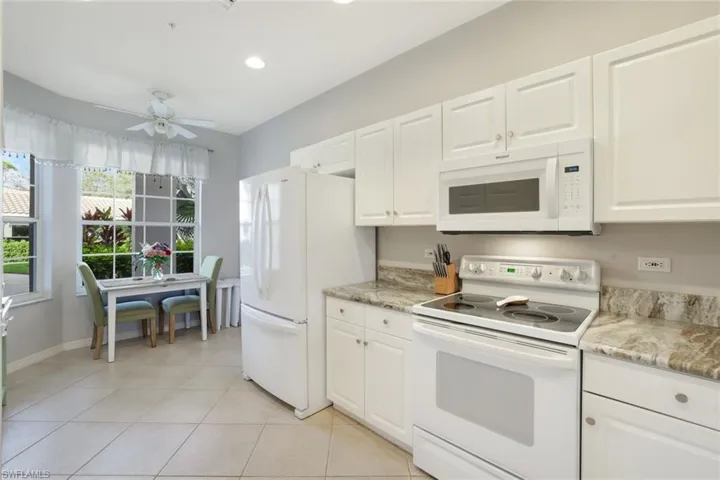Kitchen featuring white appliances, light tile patterned floors, and white cabinets