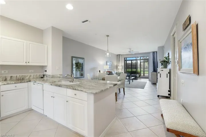 Kitchen featuring pendant lighting, dishwasher, sink, white cabinets, and kitchen peninsula