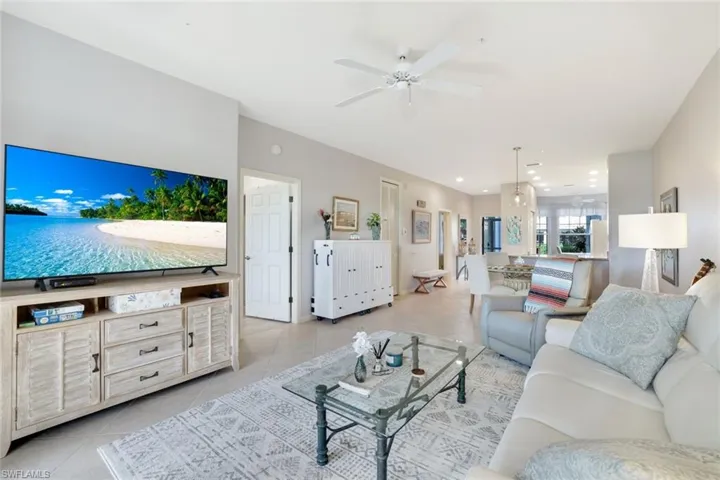 Living room with ceiling fan and light tile patterned flooring