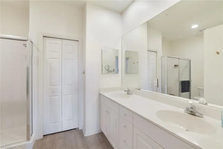 Bathroom featuring an enclosed shower, vanity, wood-type flooring, and toilet