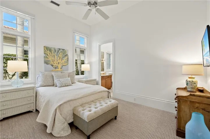 Bedroom with ceiling fan, ensuite bathroom, and light carpet