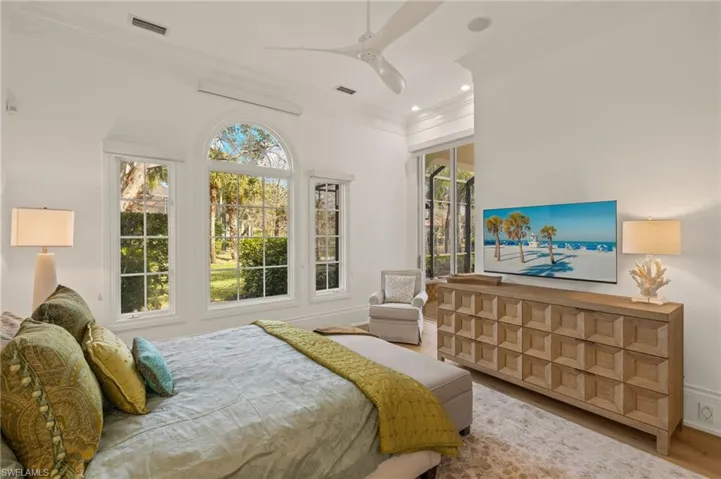 Bedroom featuring multiple windows, access to exterior, hardwood / wood-style flooring, and ornamental molding