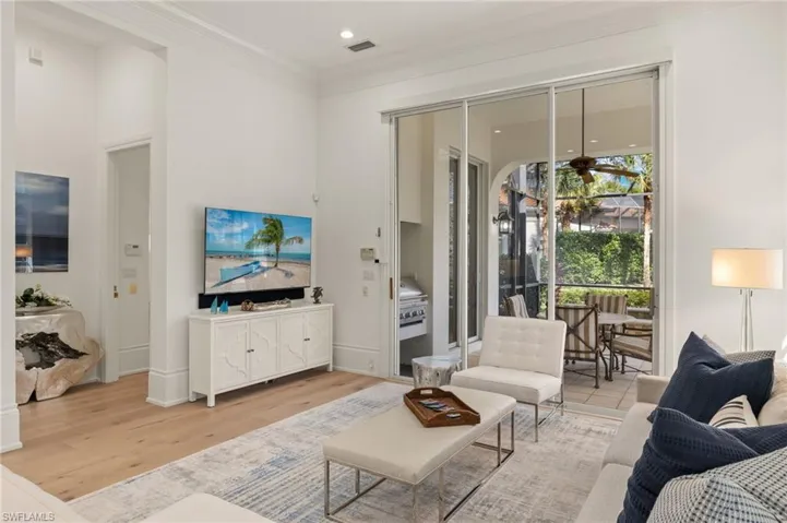 Living room with light hardwood / wood-style flooring, ornamental molding, and ceiling fan
