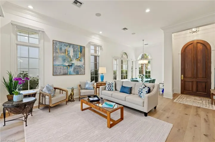 Living room with ornamental molding, a chandelier, and light hardwood / wood-style floors