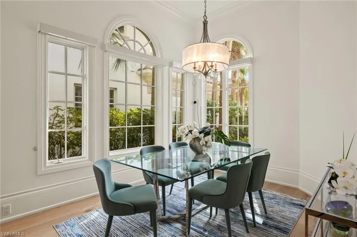 Dining area with a healthy amount of sunlight, crown molding, a chandelier, and light wood-type flooring