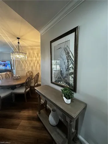 Dining space featuring crown molding, a notable chandelier, and dark wood-type flooring