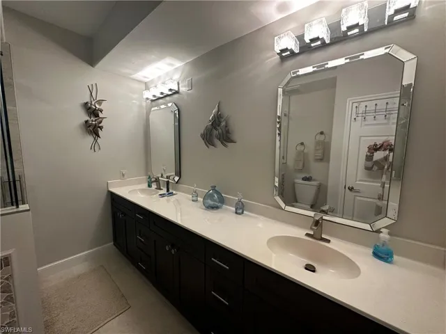 Full bathroom featuring double vanity, toilet, and a sink