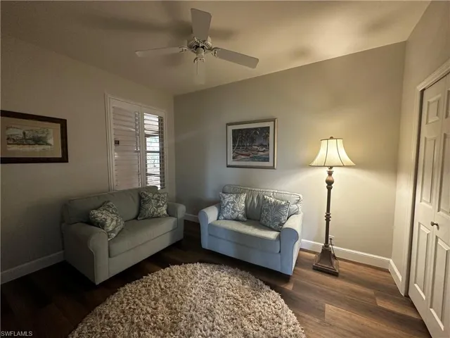 Living room featuring baseboards, dark wood-style floors, and ceiling fan