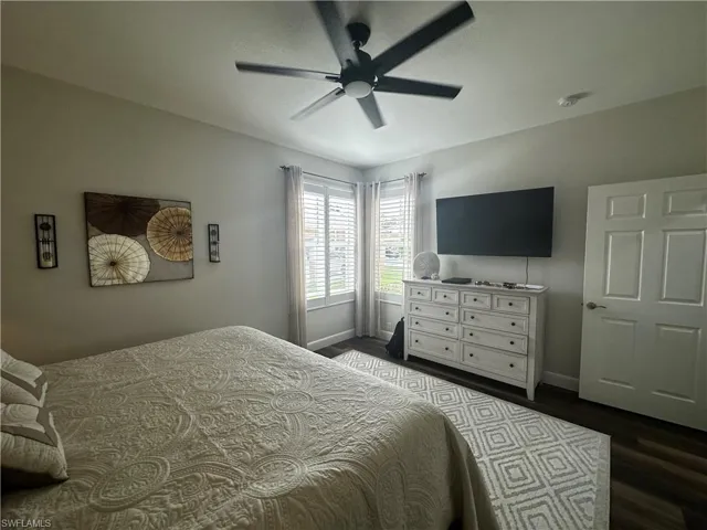 Bedroom with dark wood-style flooring, baseboards, and ceiling fan