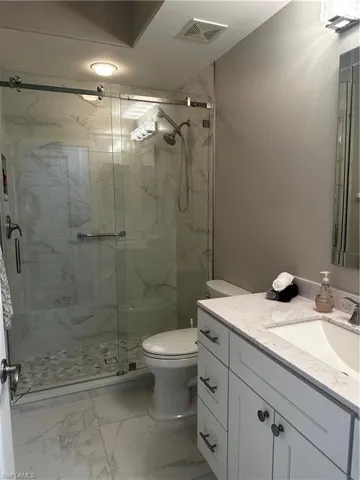 Bathroom with visible vents, vanity, marble finish floor, toilet, and a marble finish shower