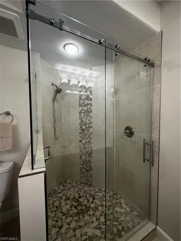 Full bath featuring toilet, visible vents, and a shower stall