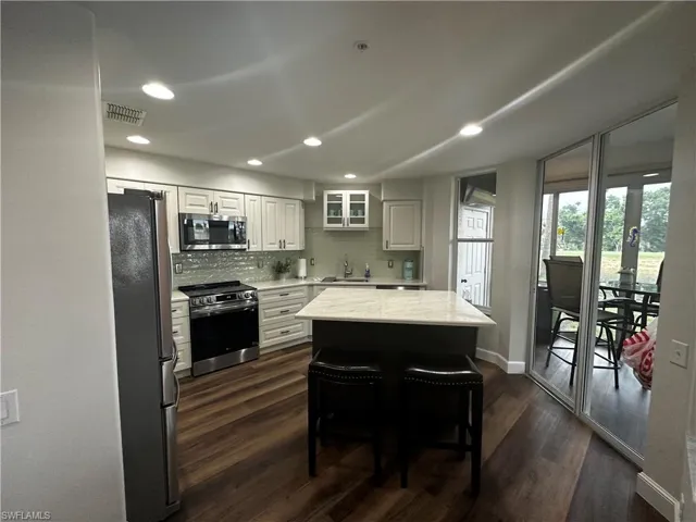 Kitchen featuring visible vents, a sink, baseboards, dark wood-style floors, and stainless steel appliances