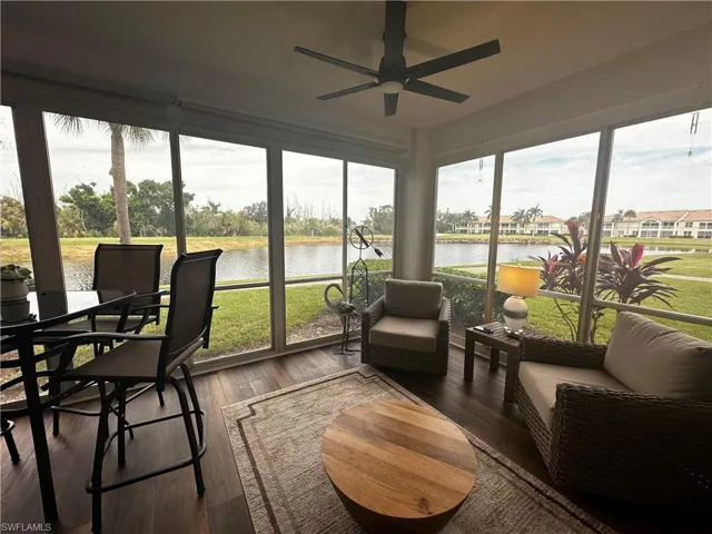 Sunroom with a water view, a ceiling fan, and wood finished floors