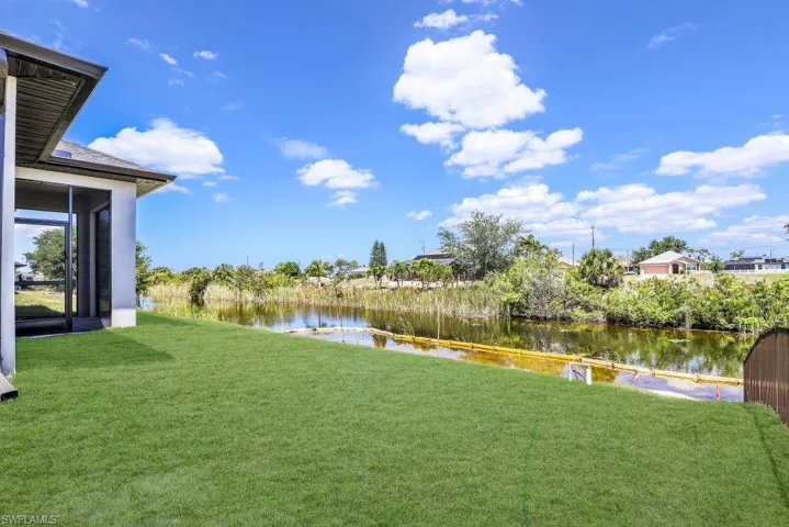 Expansive rear lawn bordering a tranquil canal