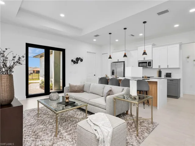 Open-concept living area featuring a modern kitchen with a large island, two-tone cabinetry, and stainless steel appliances