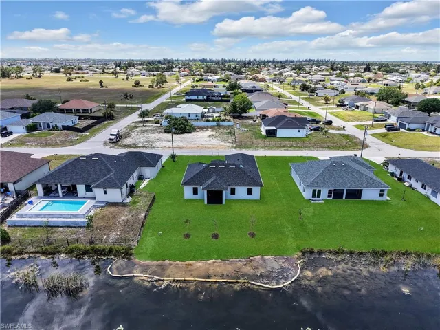 Newly constructed residence featuring a dark shingle roof, white exterior siding, and a lush green lawn