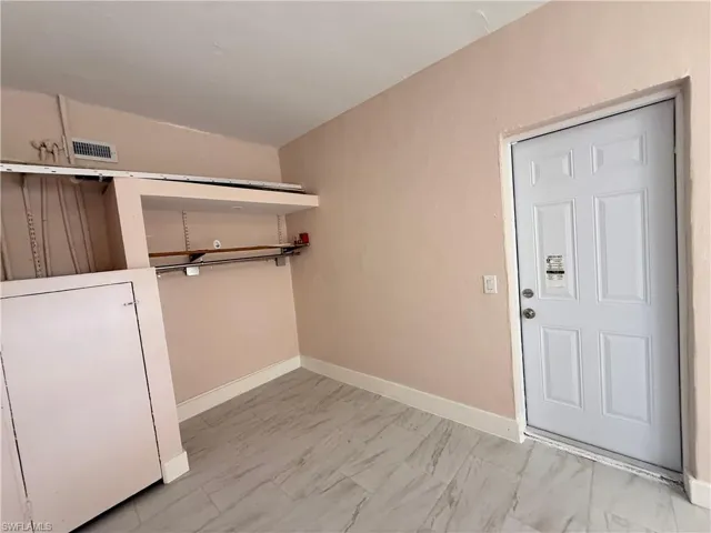 Laundry area featuring baseboards and light marble finish floors