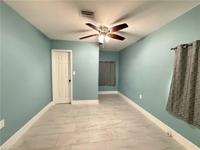 Unfurnished room featuring marble finish flooring and a ceiling fan