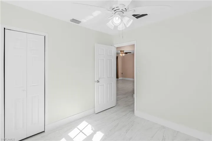 Unfurnished bedroom with light marble finish flooring, ceiling fan, and a closet