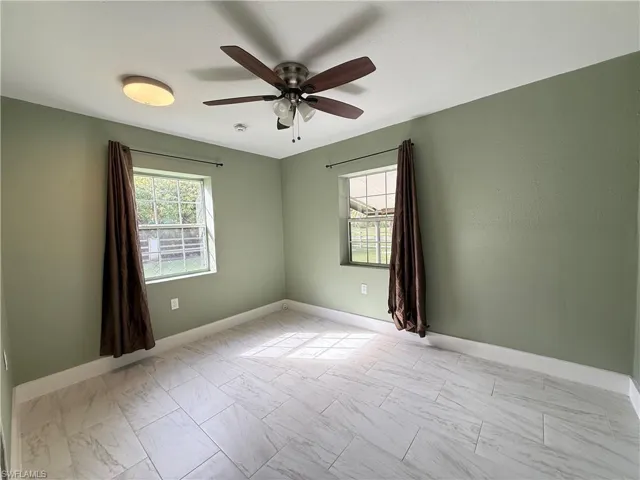 Spare room featuring plenty of natural light, ceiling fan, and light marble finish floors
