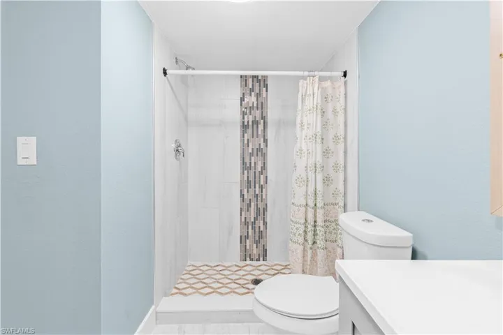 Bathroom featuring vanity, a shower stall, and a textured wall