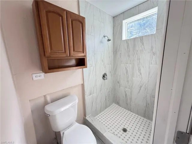 Bathroom with a shower stall and toilet