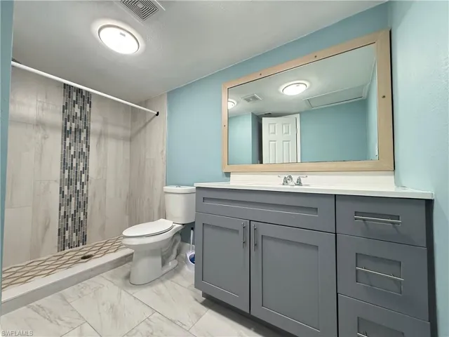 Bathroom with vanity, a stall shower, and light marble finish floors