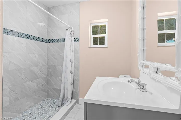 Bathroom with a stall shower, vanity, and light marble finish floors