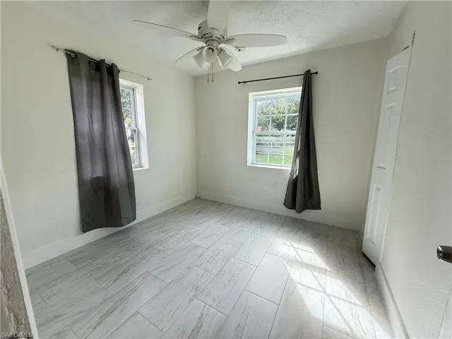 Spare room featuring a textured ceiling, a ceiling fan, and light marble finish flooring