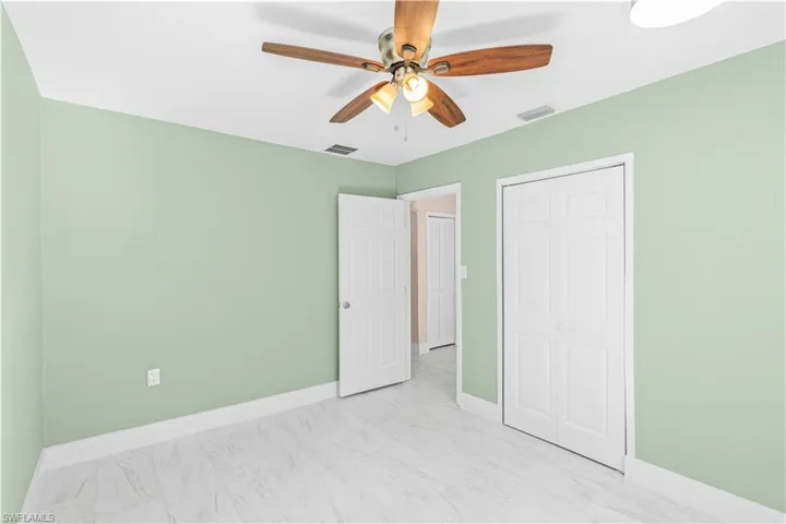 Unfurnished bedroom with ceiling fan and a closet