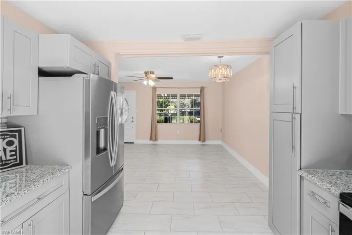 Kitchen with light stone countertops, a chandelier, ceiling fan, and decorative light fixtures