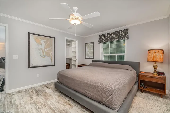 Bedroom featuring light hardwood / wood-style flooring, a spacious closet, ceiling fan, crown molding, and a closet