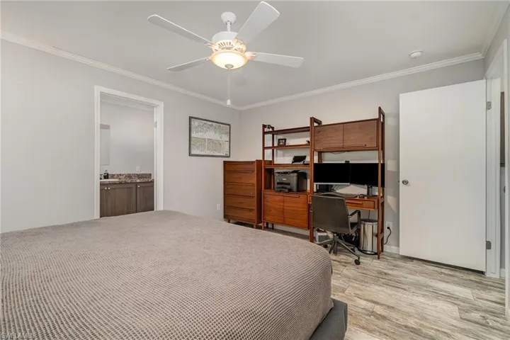 Bedroom featuring ceiling fan, ornamental molding, connected bathroom, and light hardwood / wood-style flooring