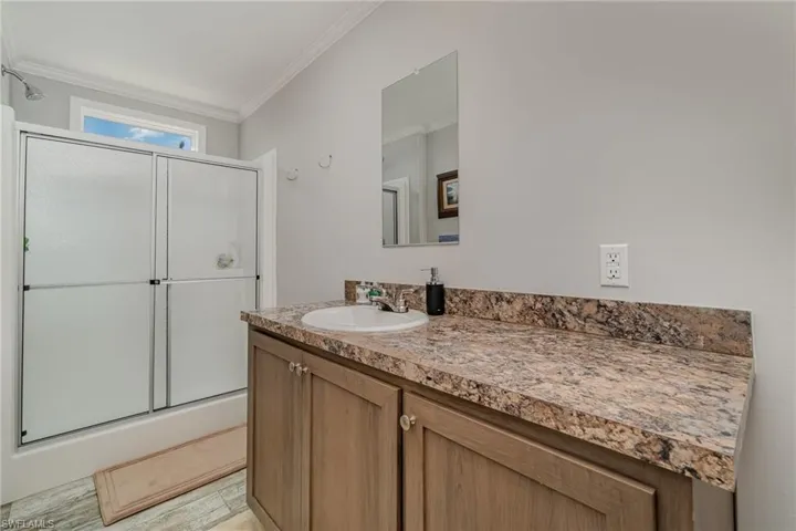 Bathroom featuring an enclosed shower, ornamental molding, and vanity