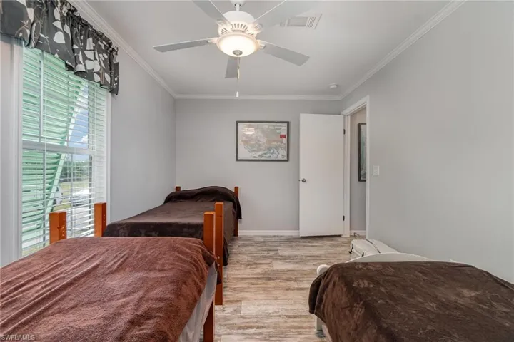 Bedroom with ceiling fan, ornamental molding, and light hardwood / wood-style flooring
