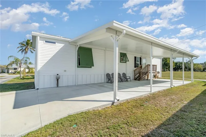 Back of property featuring a carport and a yard