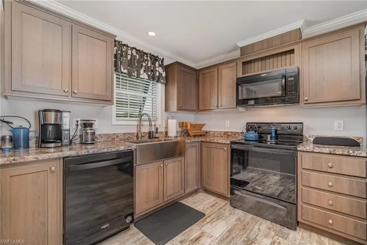 Kitchen with sink, light stone counters, and black appliances