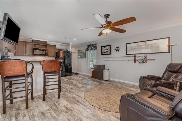 Living room featuring crown molding, light hardwood / wood-style flooring, and ceiling fan