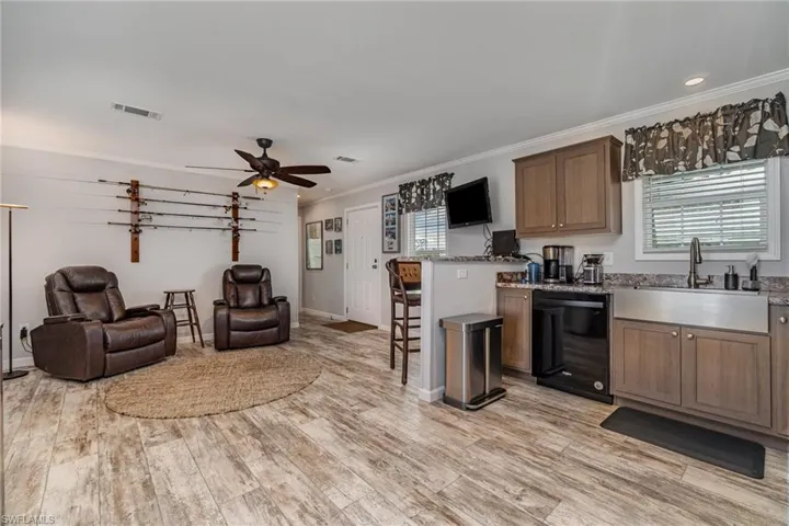 Kitchen with sink, ornamental molding, a kitchen breakfast bar, dishwasher, and light hardwood / wood-style floors