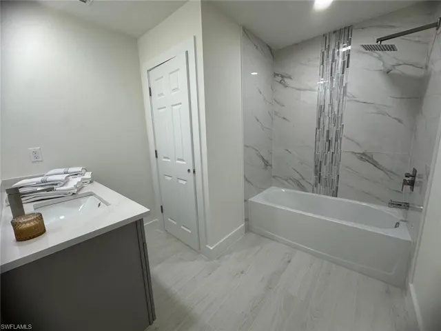 Full bath featuring a combined bath / shower with marble appearance and vanity
