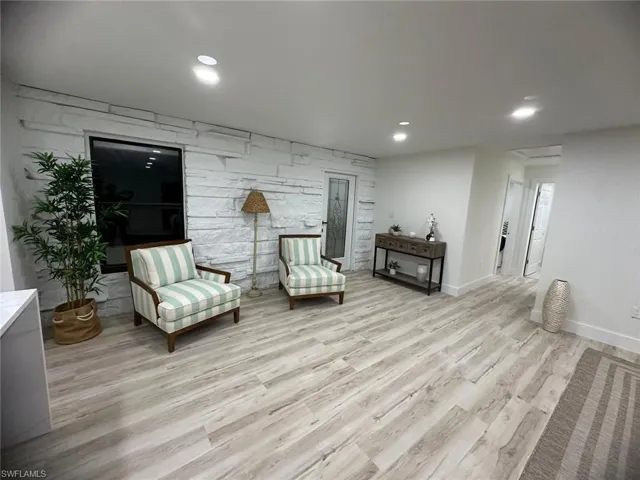 Living area featuring light wood-type flooring, recessed lighting, and an accent wall