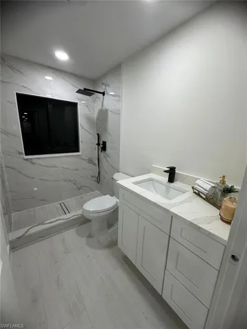 Bathroom featuring vanity, a marble finish shower, and recessed lighting
