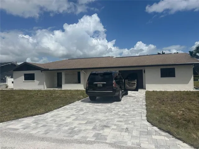 Single story home with a front lawn, decorative driveway, stucco siding, and roof with shingles