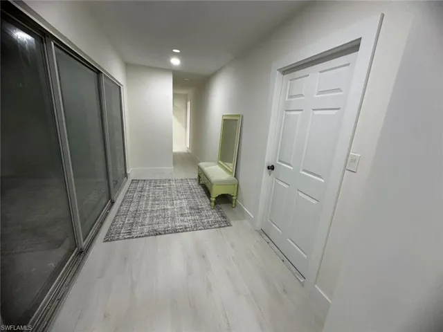 Corridor with light wood-type flooring and recessed lighting