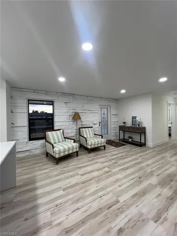 Sitting room with light wood-style floors, an accent wall, and recessed lighting